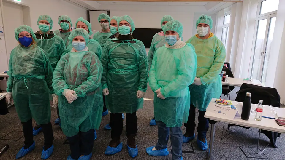 Teilnehmende üben das An- und Ausziehen von Schutzkleidung (Dezember 2021)